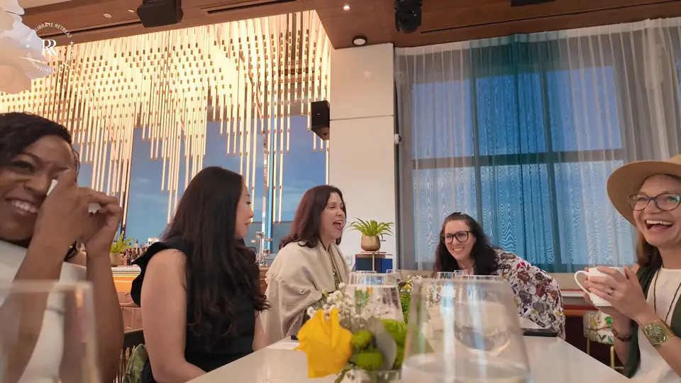 Attendees laughing together around a table during a session